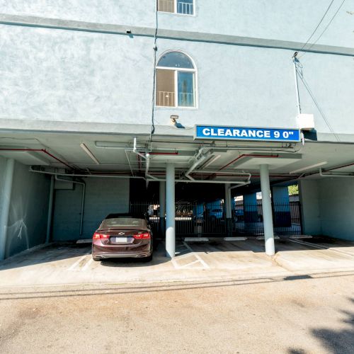 A parking area with a clearance sign of 9 feet, showing a parked car under a building's overhang.